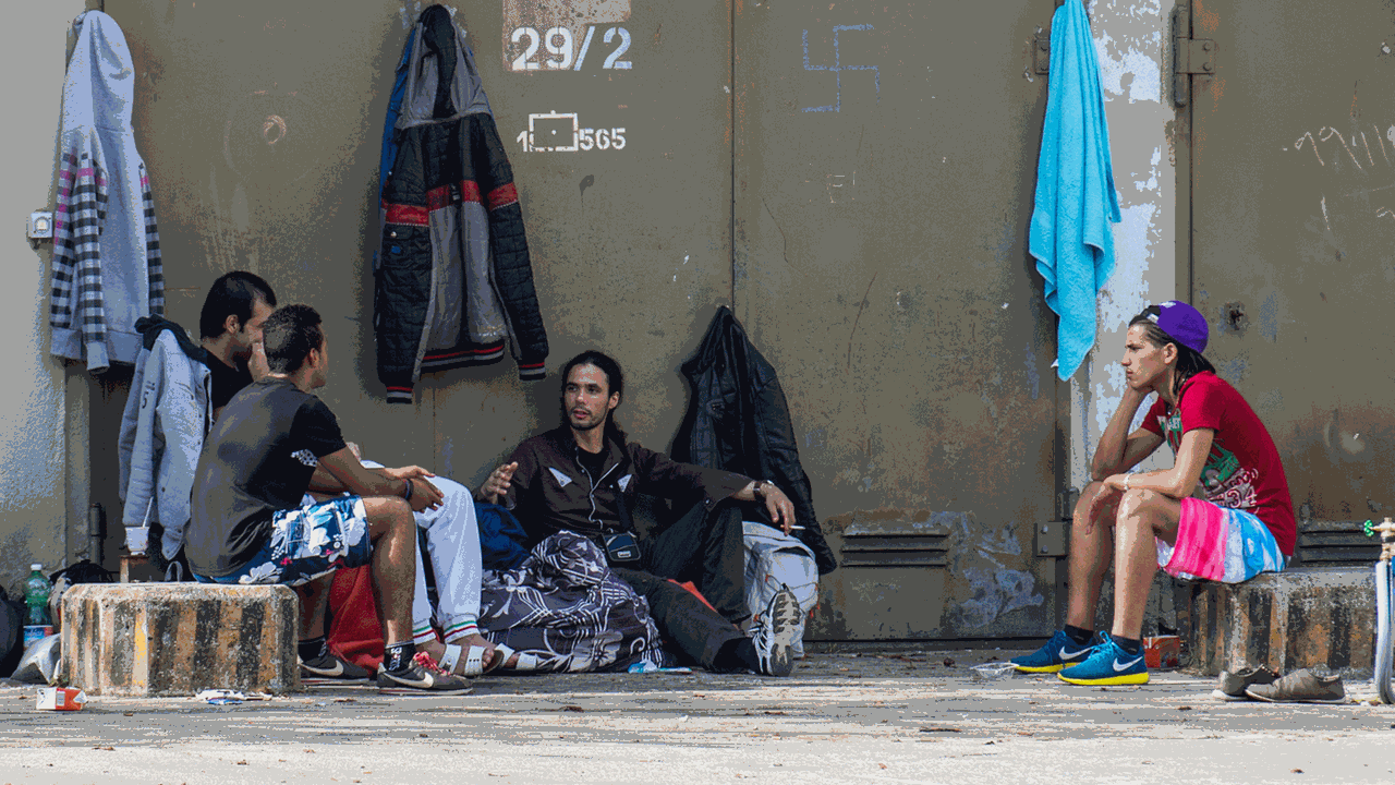 Mehrere Flüchtlinge sitzen am 10.10.2014 in München (Bayern) auf dem Gelände der Bayernkaserne neben ihren Koffern auf dem Asphalt. Am Abend zuvor haben rund 150 Flüchtlinge für eine bessere Unterbringung demonstriert.