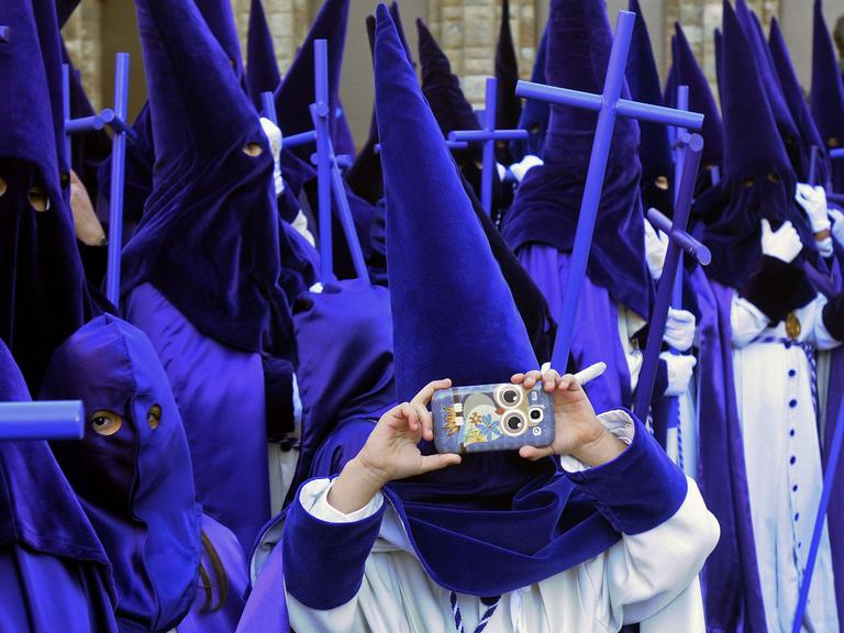 Ein Teilnehmer der traditionellen Oster-Prozession in Leon in Spanien macht am 5.4.2015 ein Foto mit seinem Smartphone.