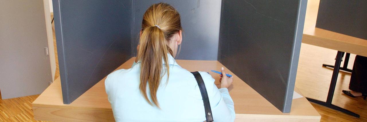 Eine junge Frau sitzt in einer Wahl-Kabine. Eine junge Frau sitzt in einer Wahl-Kabine.