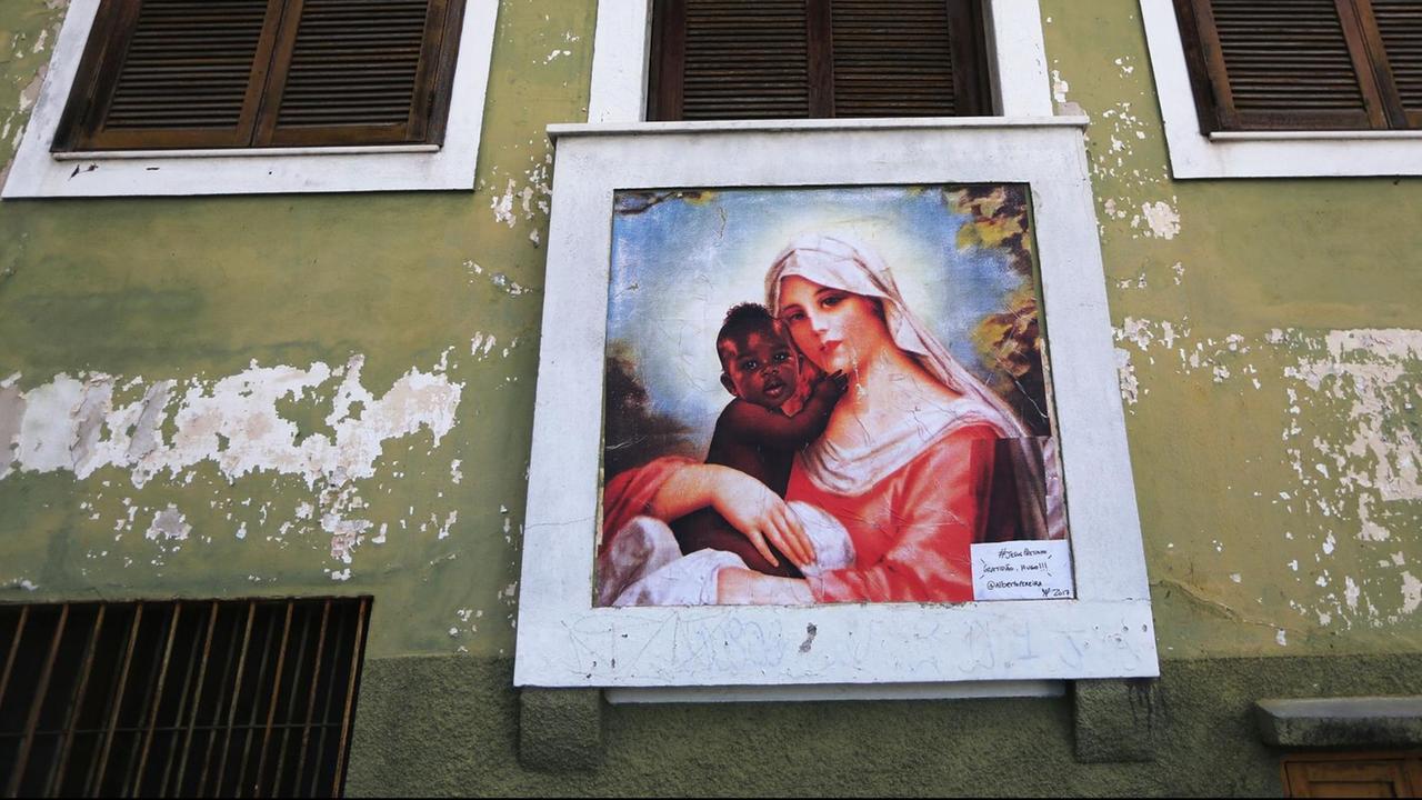 Ein Porträt der Jungfrau Maria mit einem dunkelhäutigen Baby im Arm an einer Hauswand einer Favela in Rio de Janeiro.