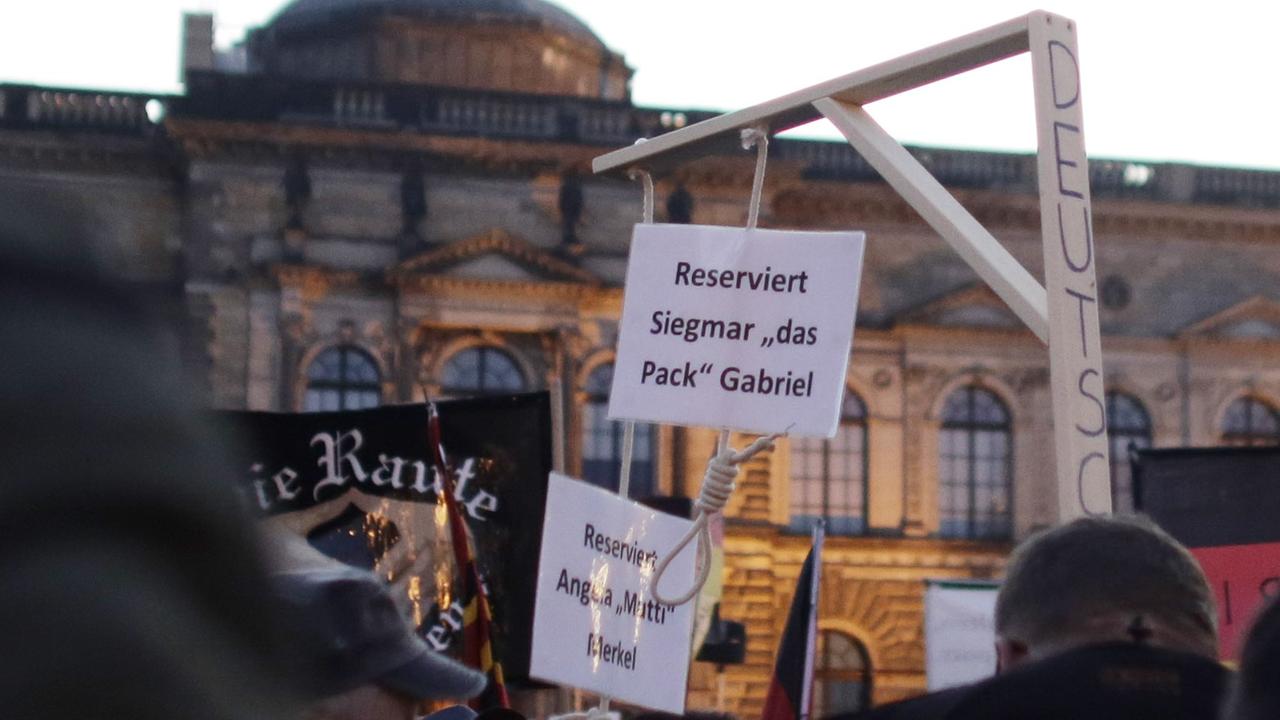 Auf einer Kundgebung der fremdenfeindlichen Pegida-Bewegung in Dresden am 12.10.2015 hält ein Demonstrant einen Galgen hoch, an dem zwei Schilder hängen. Darauf steht "Reserviert für Angela Merkel" und "Reserviert für Siegmar Gabriel". Auf einer Kundgebung der fremdenfeindlichen Pegida-Bewegung in Dresden am 12.10.2015 hält ein Demonstrant einen Galgen hoch, an dem zwei Schilder hängen. Darauf steht "Reserviert für Angela Merkel" und "Reserviert für Siegmar Gabriel".