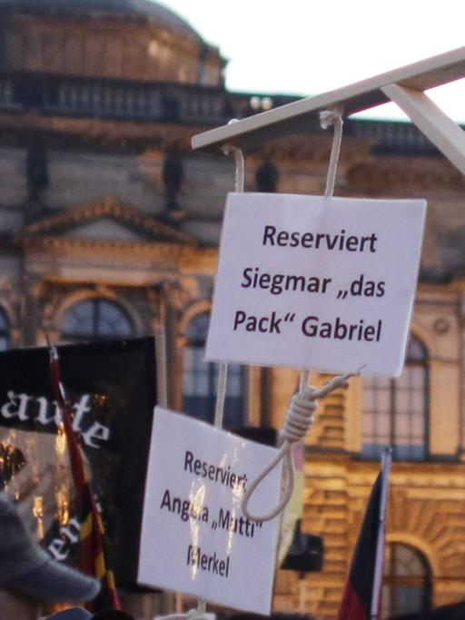 Auf einer Kundgebung der fremdenfeindlichen Pegida-Bewegung in Dresden am 12.10.2015 hält ein Demonstrant einen Galgen hoch, an dem zwei Schilder hängen. Darauf steht "Reserviert für Angela Merkel" und "Reserviert für Siegmar Gabriel".