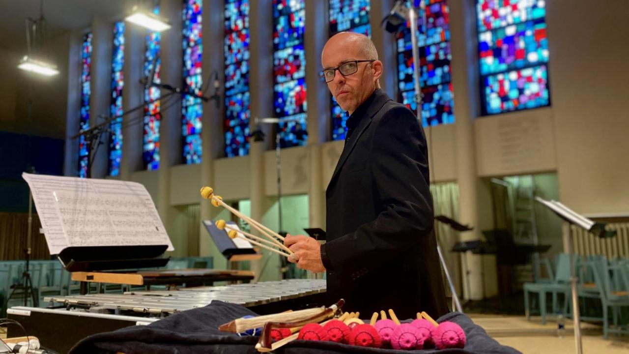 Der Percussionist schaut zur Kamera über seine zurechtgelegten Schlegel. Der Percussionist schaut zur Kamera über seine zurechtgelegten Schlegel.