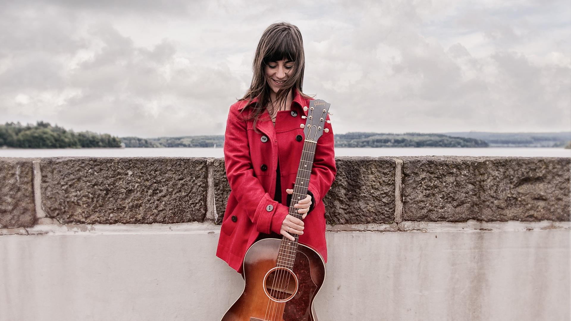 Die Musikerin Linda Sutti hält eine Gitarre in den Händen. Die Musikerin Linda Sutti hält eine Gitarre in den Händen.