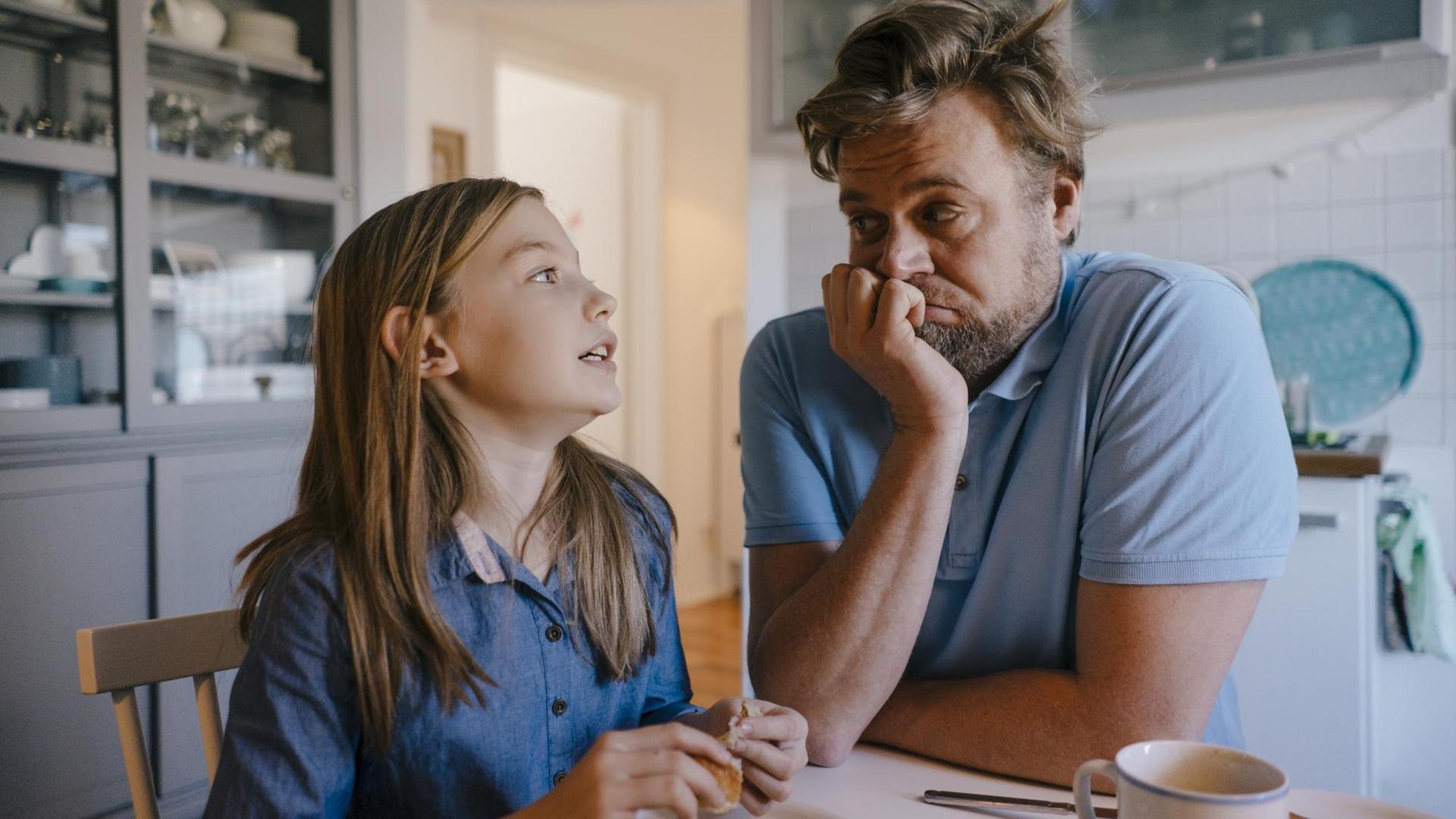 Eine Tochter erklärt am Küchentisch dem Vater etwas, dieser grübelt etwas verzweifelt darüber nach. Eine Tochter erklärt am Küchentisch dem Vater etwas, dieser grübelt etwas verzweifelt darüber nach.