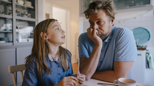 Eine Tochter erklärt am Küchentisch dem Vater etwas, dieser grübelt etwas verzweifelt darüber nach.
