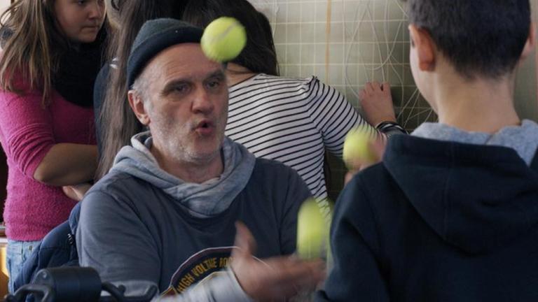 Herr Bachmann jongliert mit Tennisbällen. Um ihn herum Schülerinnen und Schüler. Herr Bachmann jongliert mit Tennisbällen. Um ihn herum Schülerinnen und Schüler.