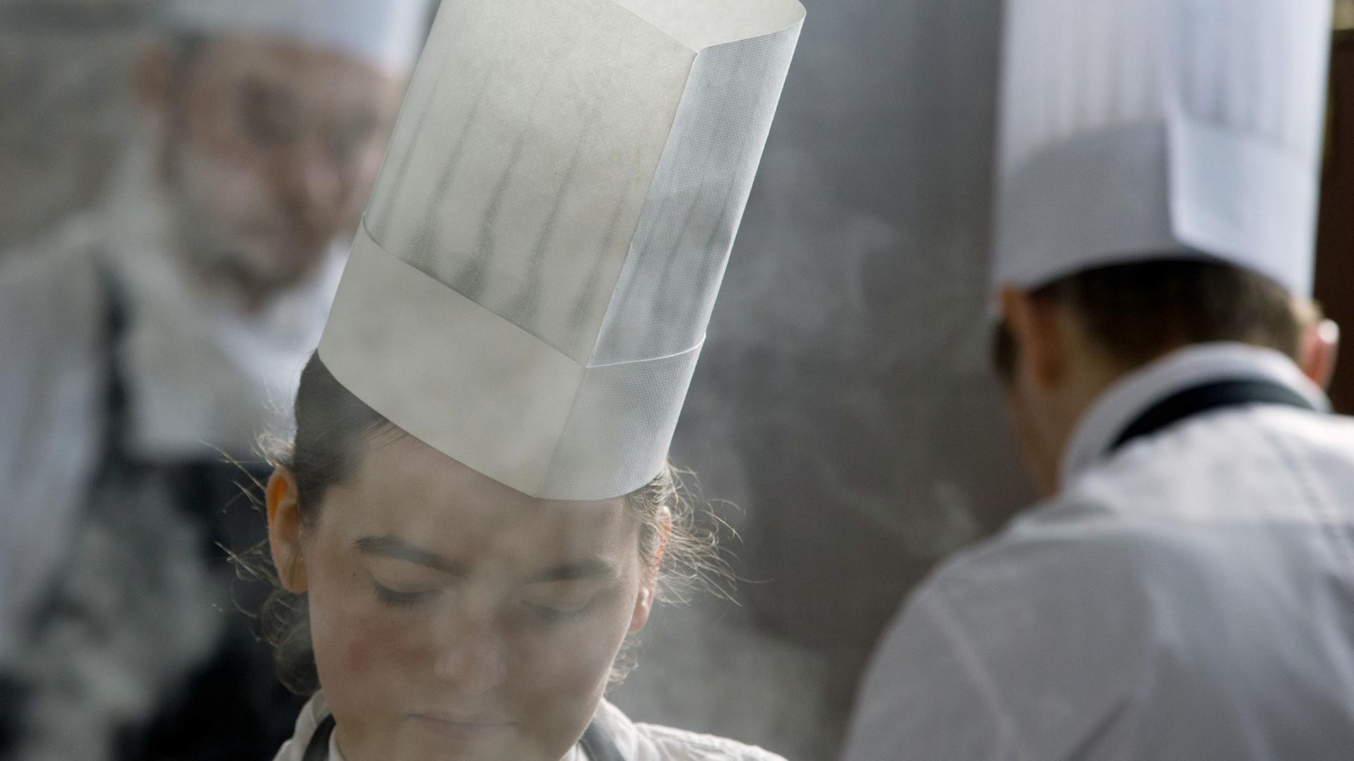 Drei Köche mit Kochmützen arbeiten in einer Restaurantküche. Drei Köche mit Kochmützen arbeiten in einer Restaurantküche.