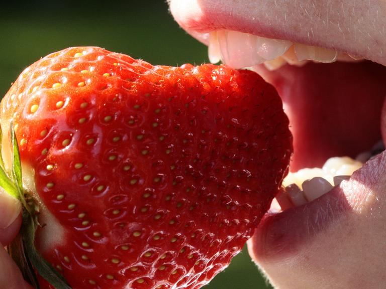 Eine Frau probiert eine Erdbeere