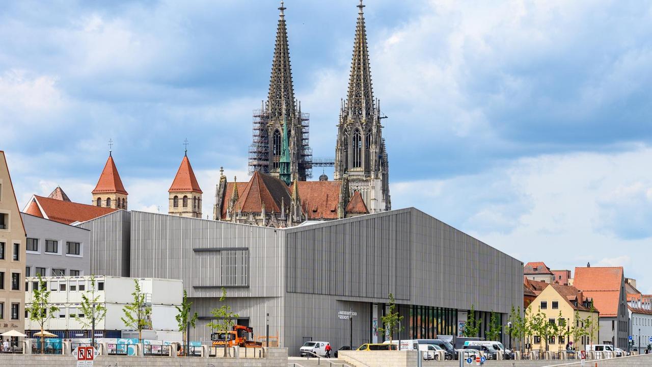 Das Museum der Bayerischen Geschichte am Regensburger Donauufer. Ein architektonisch postmodernes Gebäude am Ufer eines Flusses hebt sich ab vor einem Dom im Hintergrund. Das Museum der Bayerischen Geschichte am Regensburger Donauufer. Ein architektonisch postmodernes Gebäude am Ufer eines Flusses hebt sich ab vor einem Dom im Hintergrund.