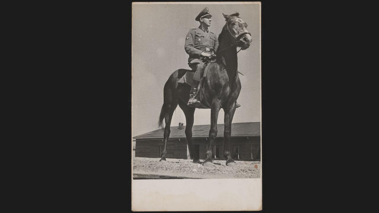 Inszenierte Aufnahme Niemanns zu Pferd im Sommer 1943. Im Hintergrund eine Wohnbaracke der Trawniki.
