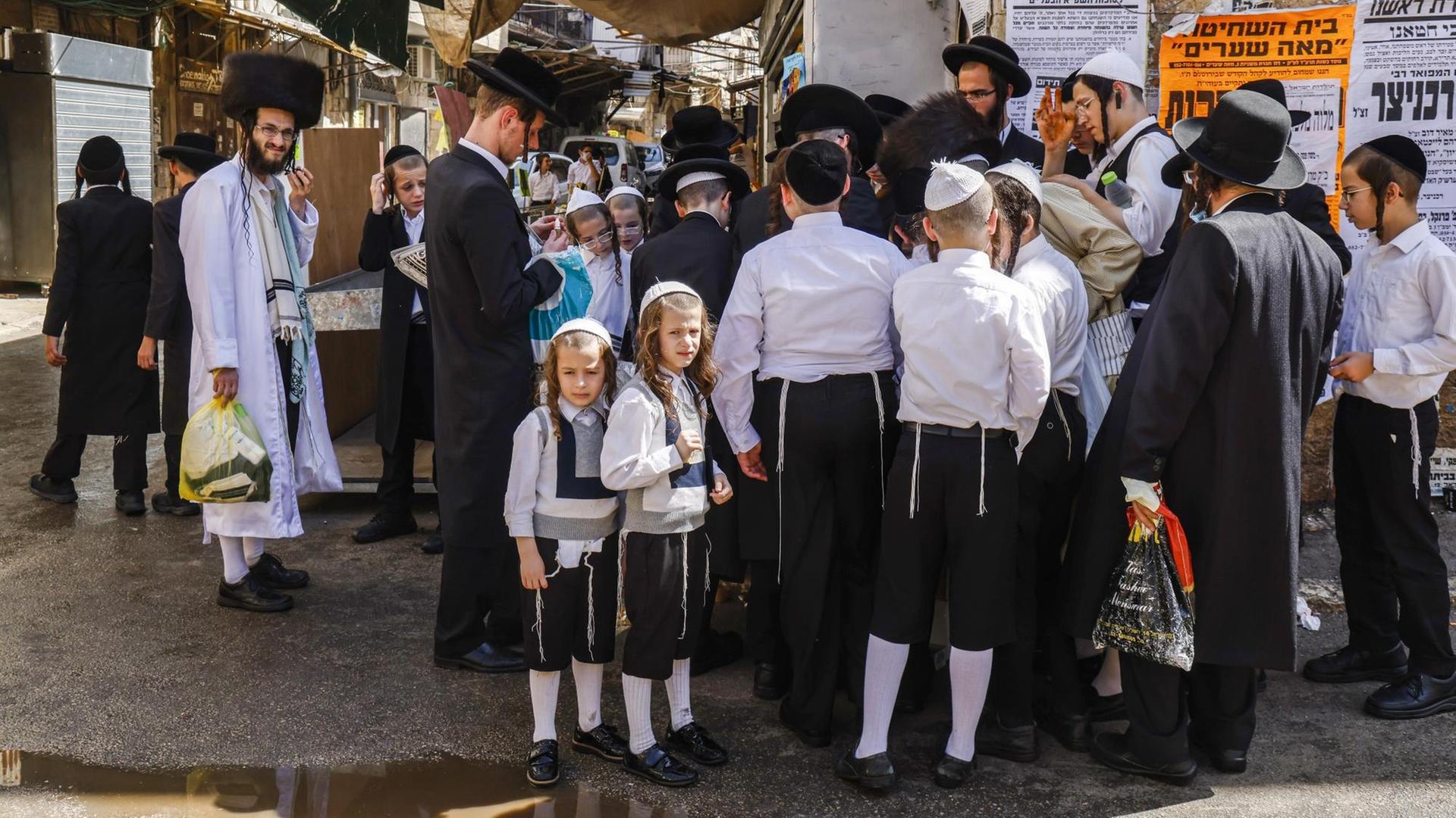 Ultra-orthodoxe jüdische Männer und Jungen stehen zusammen, einige tragen Masken. Ultra-orthodoxe jüdische Männer und Jungen stehen zusammen, einige tragen Masken.