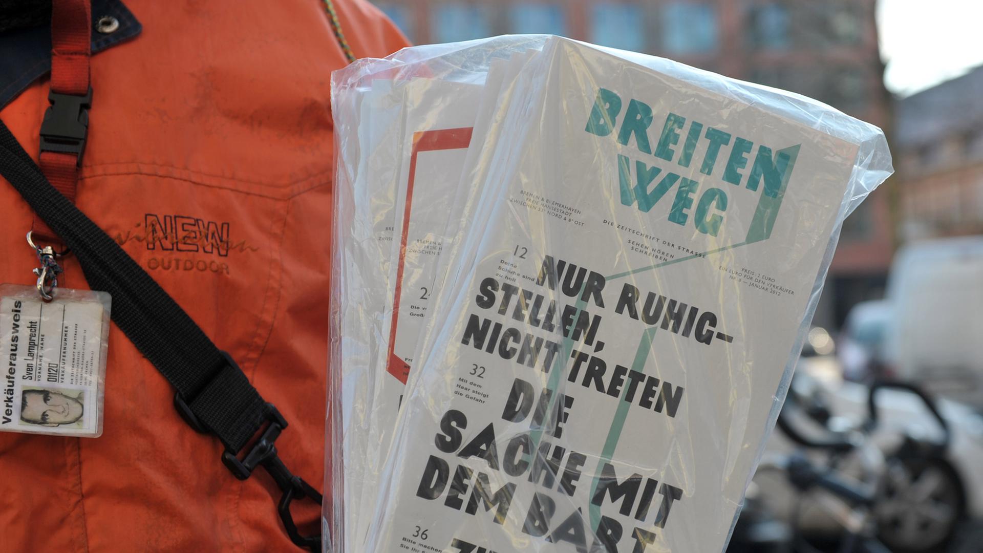 Ein Verkäufer hält die Bremer Straßenzeitung "Zeitschrift der Straße" in der Hand.