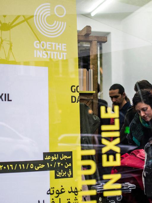 Durch eine Fensterscheibe des Veranstaltungsortes des Projekts "Goethe-Institut Damaskus im Exil" sind am 19.10.2016 in Berlin zu einer Pressekonferenz geladene Gäste zu sehen. Bei dem Projekt präsentieren etwa 100 Künstler vom 20. Oktober bis 5. November ein Programm zu den Themen Heimat, Flucht und Identität.