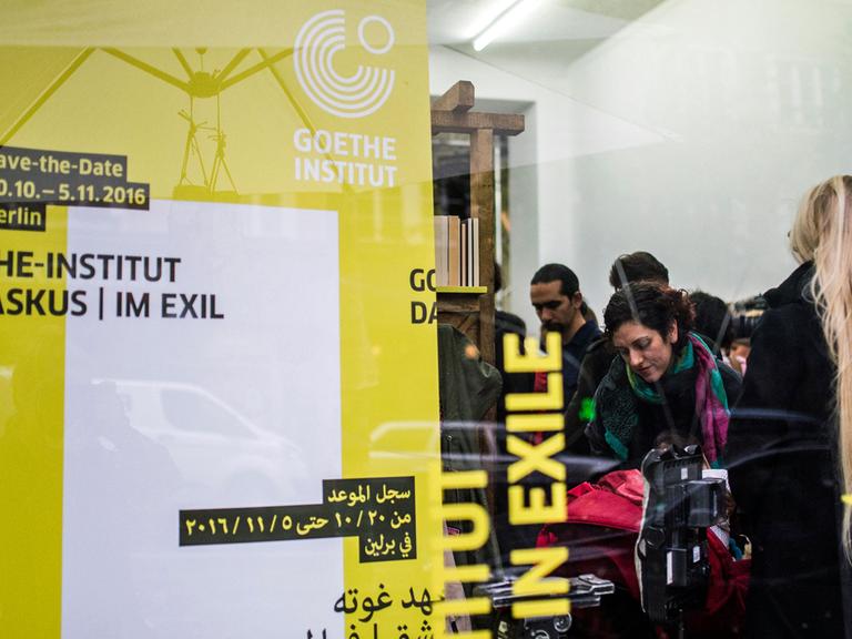 Durch eine Fensterscheibe des Veranstaltungsortes des Projekts "Goethe-Institut Damaskus im Exil" sind am 19.10.2016 in Berlin zu einer Pressekonferenz geladene Gäste zu sehen. Bei dem Projekt präsentieren etwa 100 Künstler vom 20. Oktober bis 5. November ein Programm zu den Themen Heimat, Flucht und Identität.