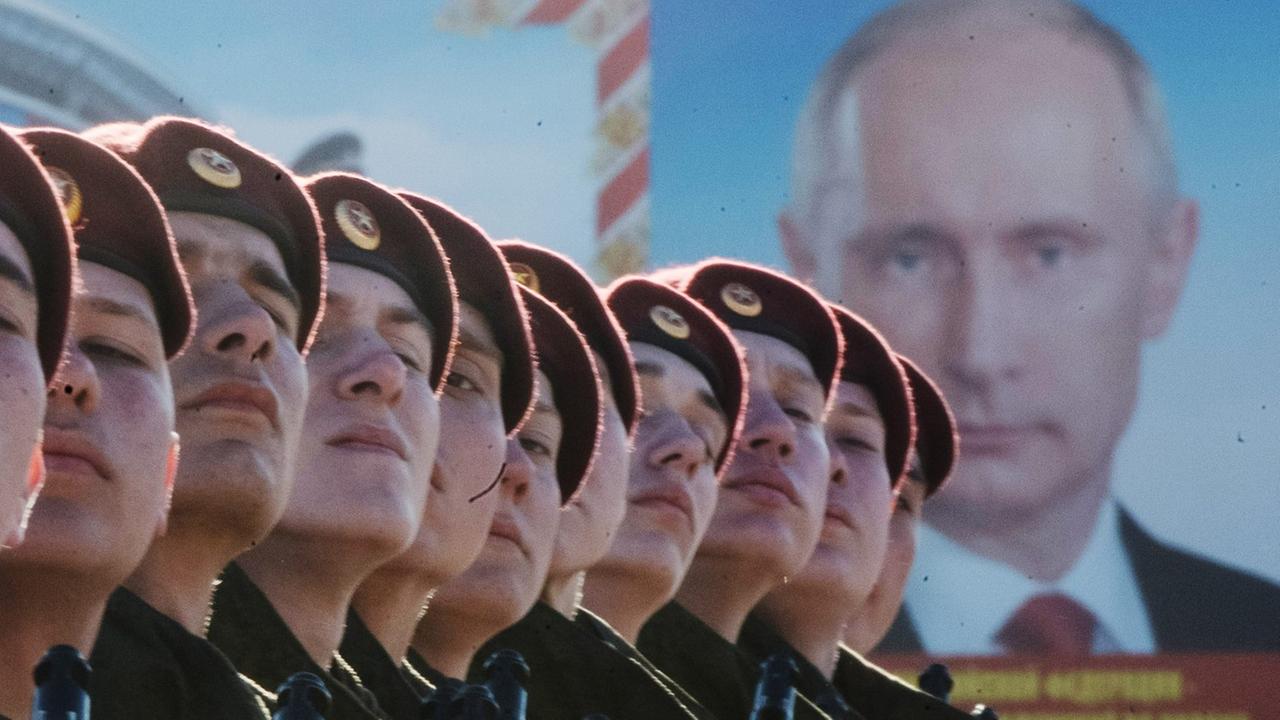 Russische Truppen vor einem Plakat des russischen Präsidenten Wladimir Putin