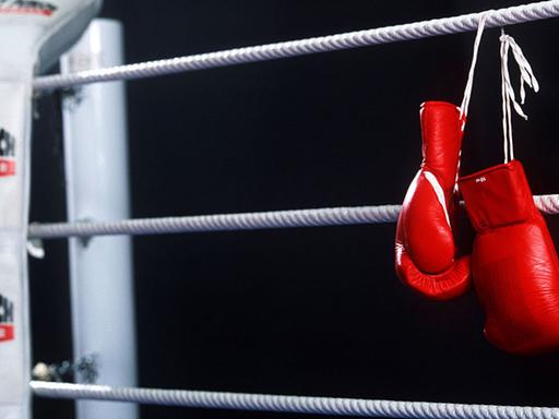 Boxhandschuhe hängen über das Seil eines Boxrings.