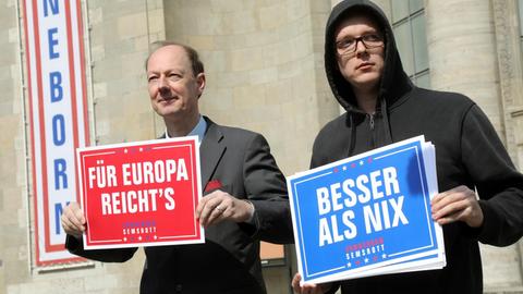 Martin Sonneborn (Die PARTEI), Vorsitzender, und Nico Semsrott halten anlässlich des EU-Wahlkampfs 2019 Plakate in den Händen, auf denen steht: "für Europa reicht's" und "Besser als Nix"