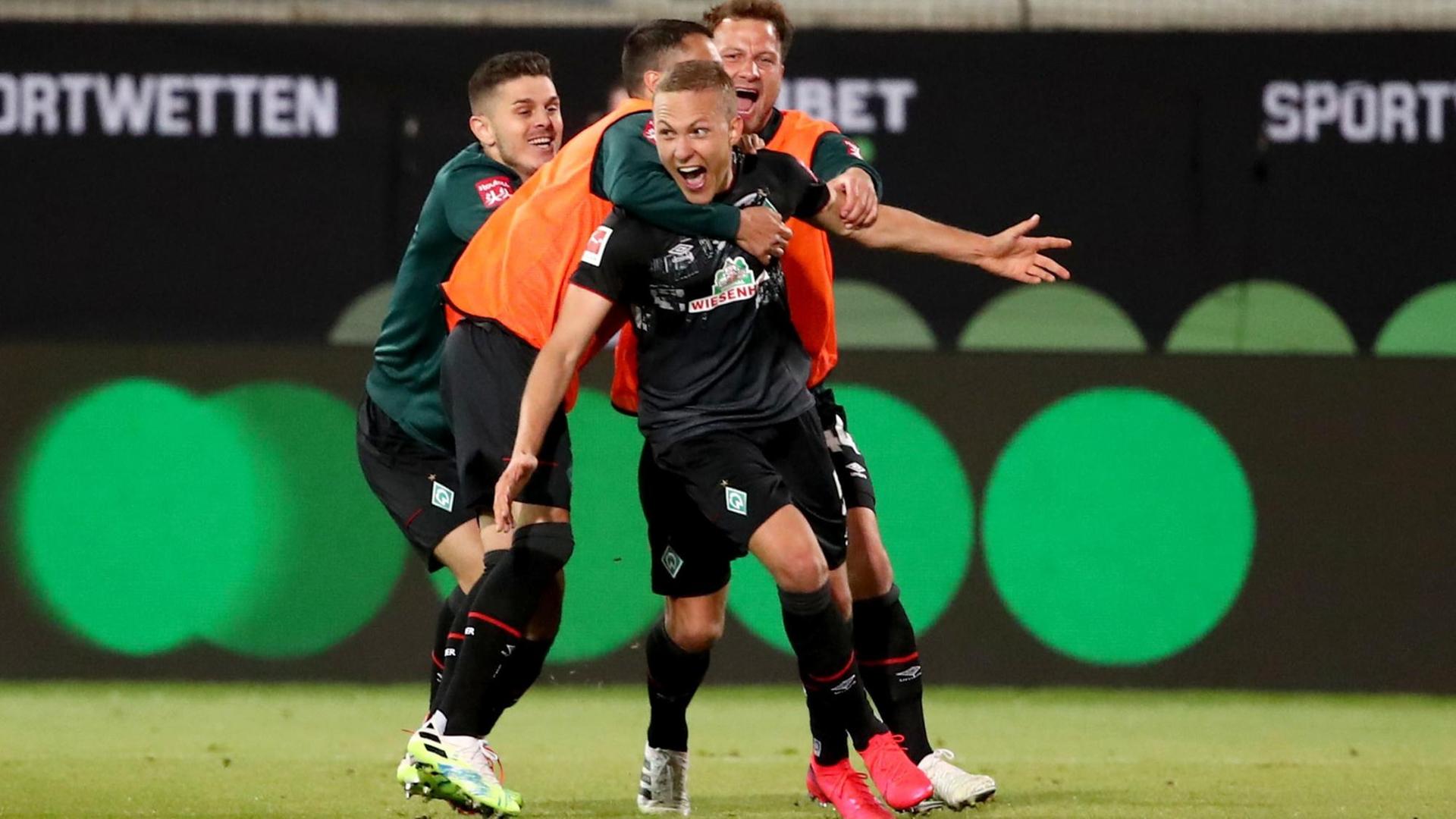 Spieler von Werder Bremen feiern auf dem Fußball-Feld.