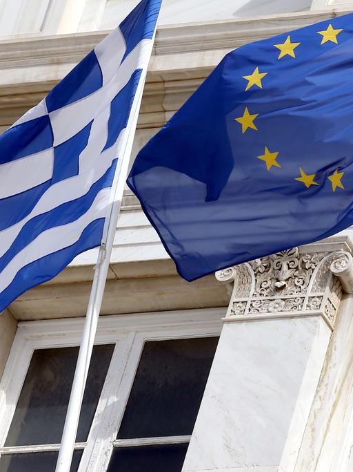Die griechische und die europäische Flagge wehen am 06.03.2014 vor dem Parlamentsgebäude in Athen. Foto: Wolfgang Kumm/dpa