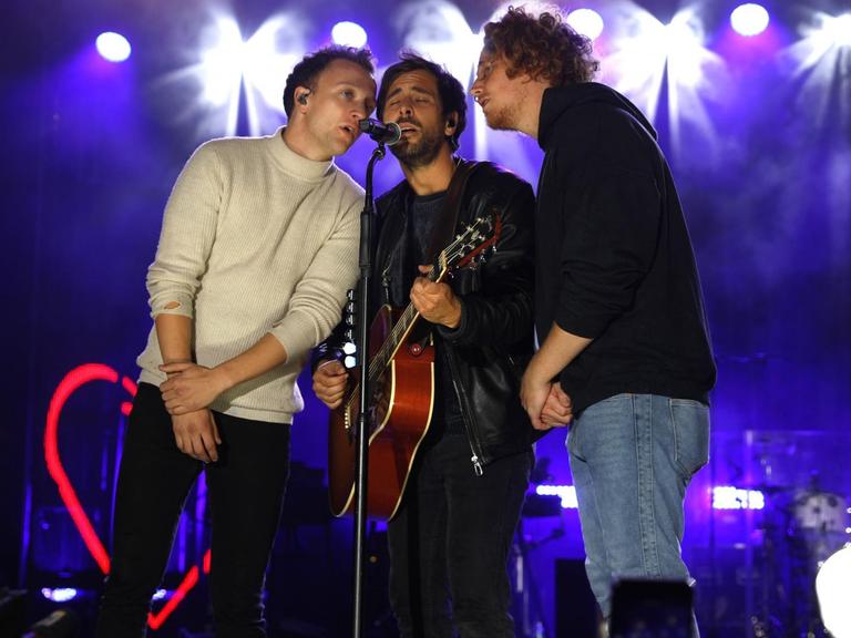Joris, Max Giesinger und Michael Schulte singen zu dritt in ein Mikrofon.