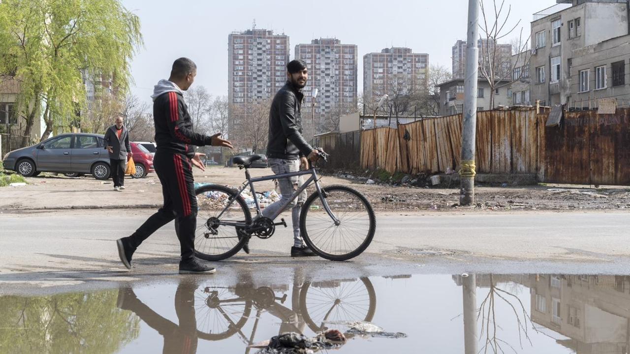 In Stolipinowo finden 90 Prozent der Bewohner keine regelmäßige Anstellung. Die Roma-Siedlung im Nordosten von Plowdiw ist die größte auf dem Balkan. Auf dem Bild laufen zwei Männer an einer Pfütze vorbei. Im Hintergrund sind Müll und grauen Wohnblocks zu sehen. In Stolipinowo finden 90 Prozent der Bewohner keine regelmäßige Anstellung. Die Roma-Siedlung im Nordosten von Plowdiw ist die größte auf dem Balkan. Auf dem Bild laufen zwei Männer an einer Pfütze vorbei. Im Hintergrund sind Müll und grauen Wohnblocks zu sehen.