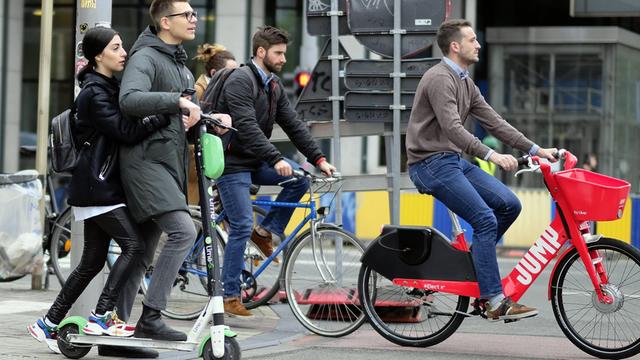 In Brüssel fährt ein Mann auf einem E-Tretroller über eine Straße.