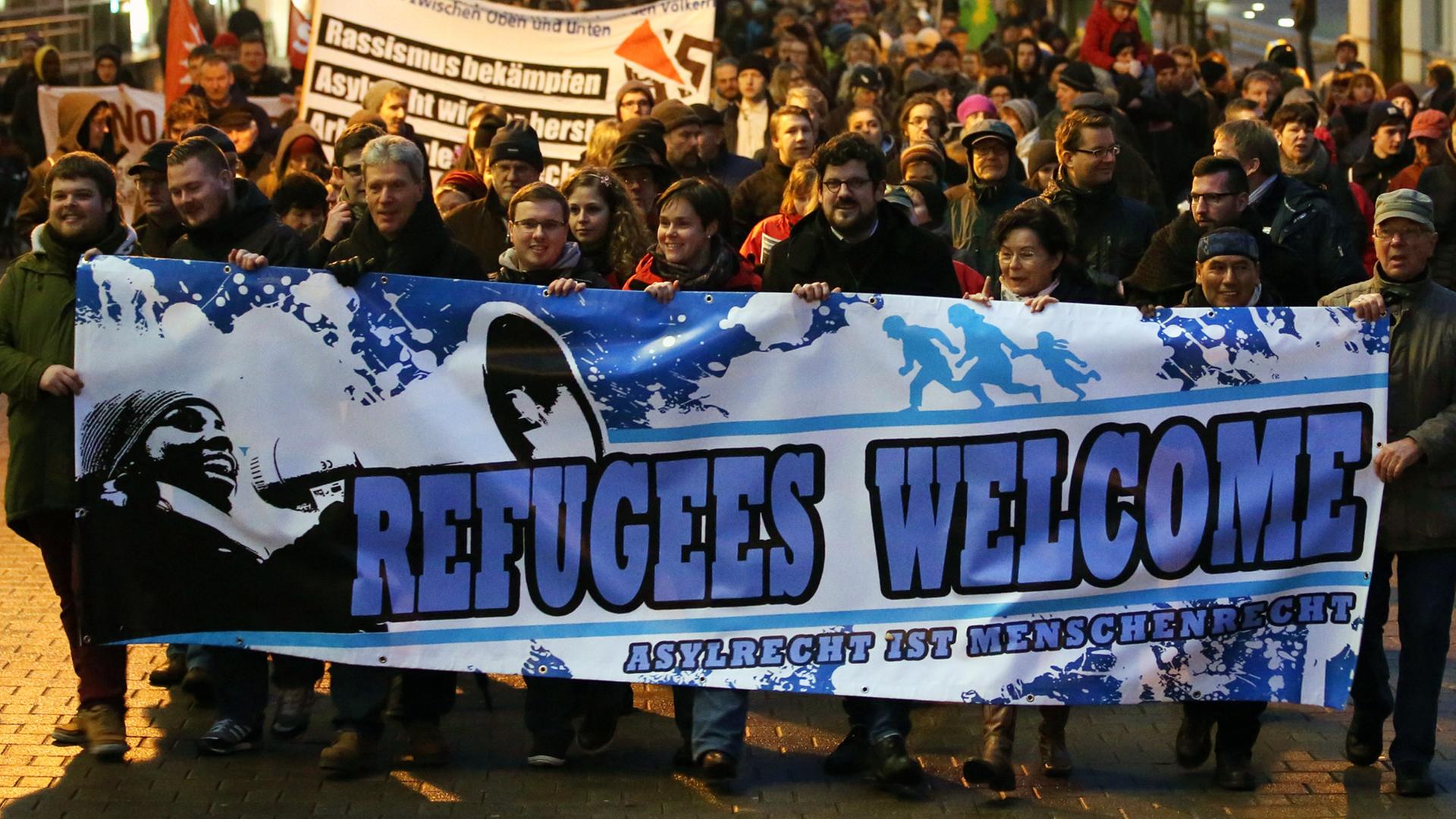 Demonstration unter dem Motto "Willkommen im Abendland - Rostock für alle" am 05.01.2015 in Rostock. Im Vordergrund ein Plakat auf dem "Refugees Welcome - Asylrecht ist Menschenrecht" steht. Demonstration unter dem Motto "Willkommen im Abendland - Rostock für alle" am 05.01.2015 in Rostock. Im Vordergrund ein Plakat auf dem "Refugees Welcome - Asylrecht ist Menschenrecht" steht.