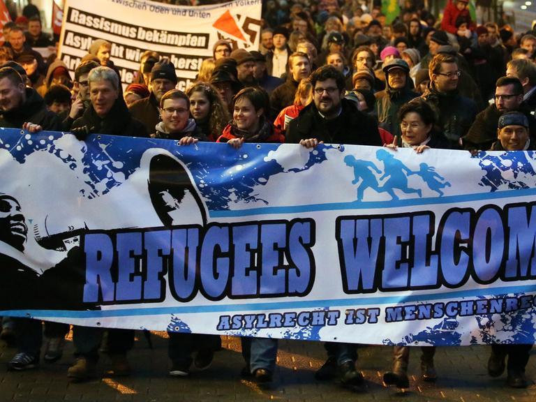 Demonstration unter dem Motto "Willkommen im Abendland - Rostock für alle" am 05.01.2015 in Rostock. Im Vordergrund ein Plakat auf dem "Refugees Welcome - Asylrecht ist Menschenrecht" steht.