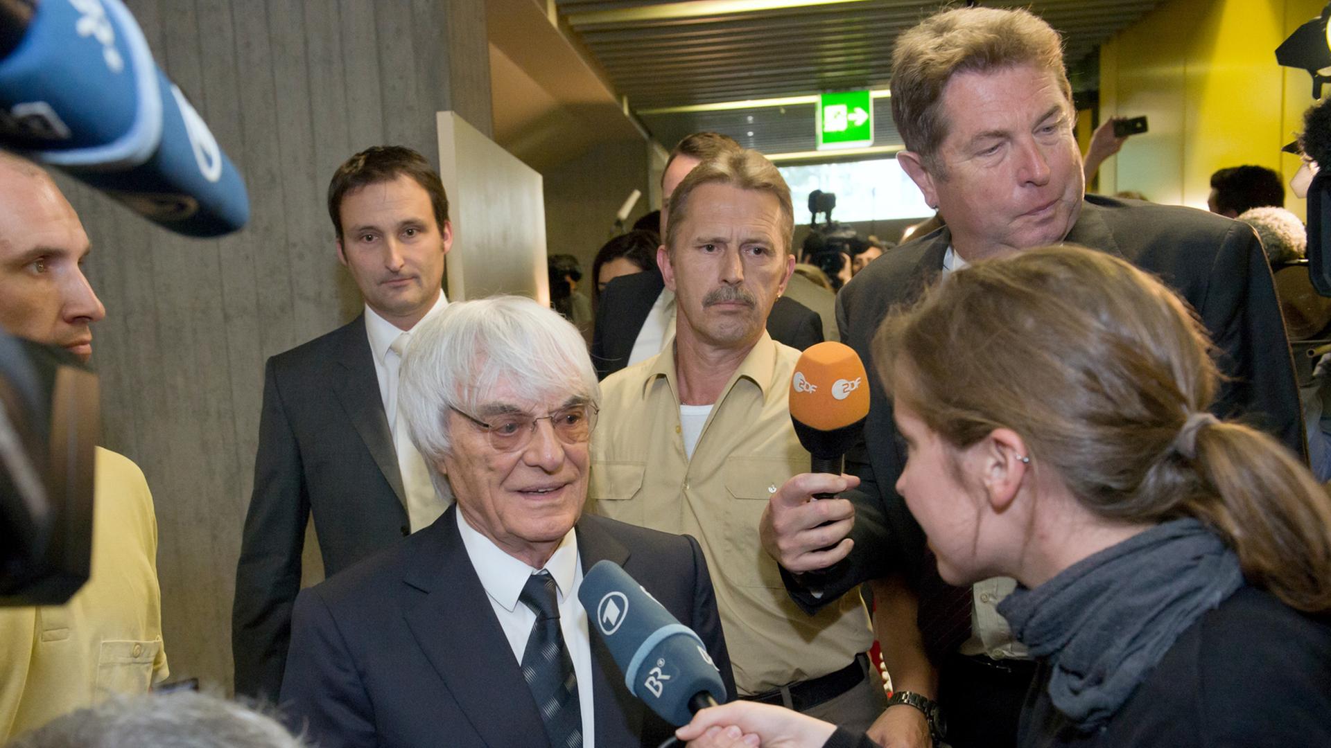 Bernie Ecclestone ist umgeben von Reportern und gibt ein Interview. Bernie Ecclestone ist umgeben von Reportern und gibt ein Interview.