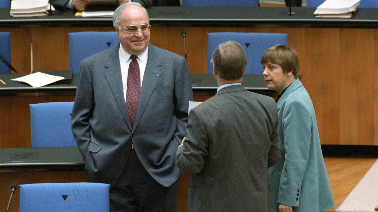 Beindruckende Macht- und Körperfülle: Bundeskanzler Helmut Kohl (CDU, links) 1995 im Deutschen Bundestag. Rechts steht die damalige Umweltministerin Angela Merkel. Beindruckende Macht- und Körperfülle: Bundeskanzler Helmut Kohl (CDU, links) 1995 im Deutschen Bundestag. Rechts steht die damalige Umweltministerin Angela Merkel.