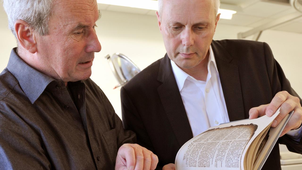 In der Restaurierungswerkstatt für brandgeschädigtes Schriftgut der Herzogin Anna Amalia Bibliothek in Weimar betrachten Bibliotheksdirektor Michael Knoche (r) und Werkstattleiter Günther Müller am Dienstag (01.09.2009) ein fertig restauriertes Buch. In der Restaurierungswerkstatt für brandgeschädigtes Schriftgut der Herzogin Anna Amalia Bibliothek in Weimar betrachten Bibliotheksdirektor Michael Knoche (r) und Werkstattleiter Günther Müller am Dienstag (01.09.2009) ein fertig restauriertes Buch.