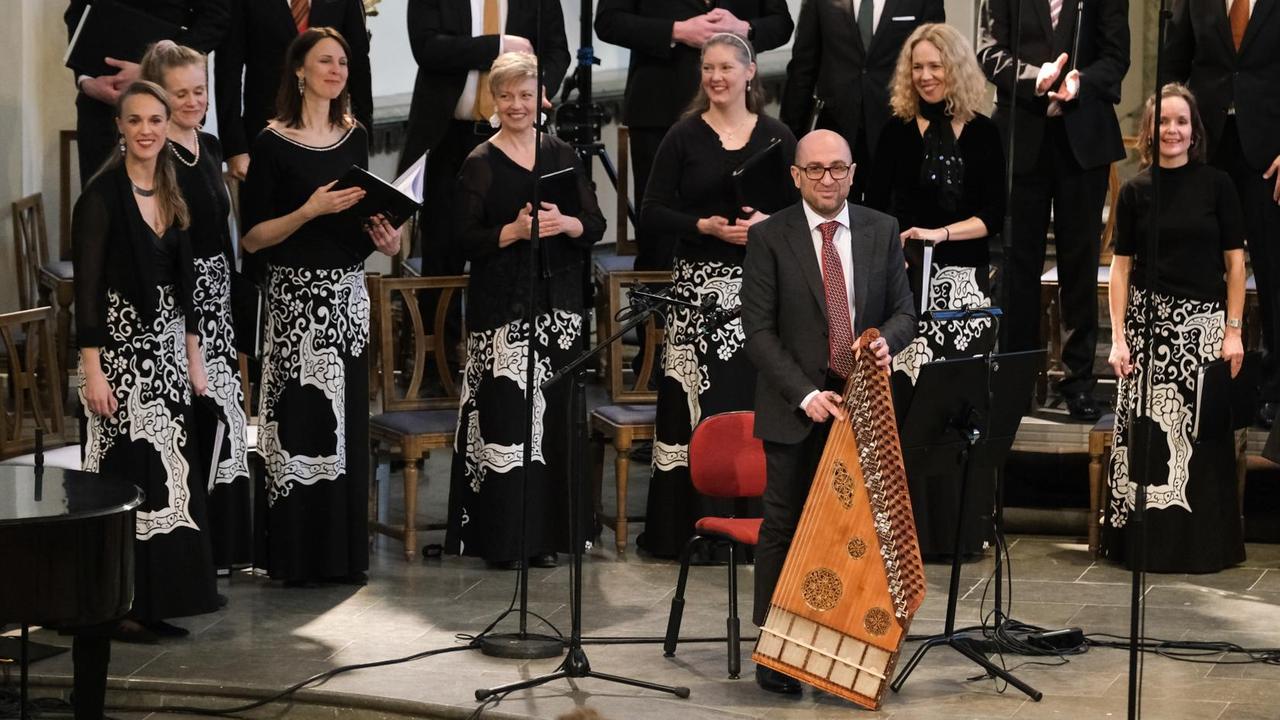 Der Kanun-Spieler präsentiert sein Zitter-artiges Instrument vor dem Chor. Der Kanun-Spieler präsentiert sein Zitter-artiges Instrument vor dem Chor.