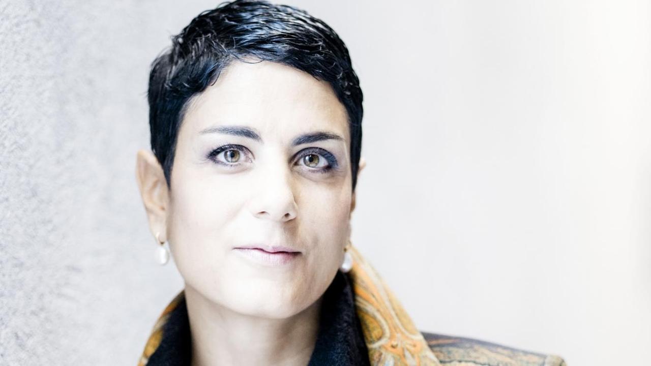 Die Musikerin Leila Schayegh lehnt gegen eine weißen Wand. Die Musikerin Leila Schayegh lehnt gegen eine weißen Wand.