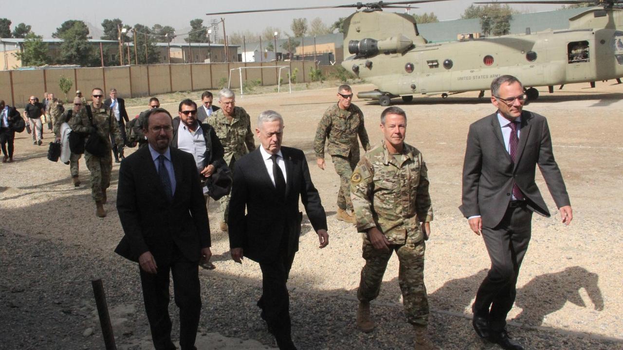 US-Verteidigungsminister Mattis geht mit Mitarbeitern und Soldaten in Kabul über einen Stützpunkt. Im Hintergrund steht ein Helikopter.