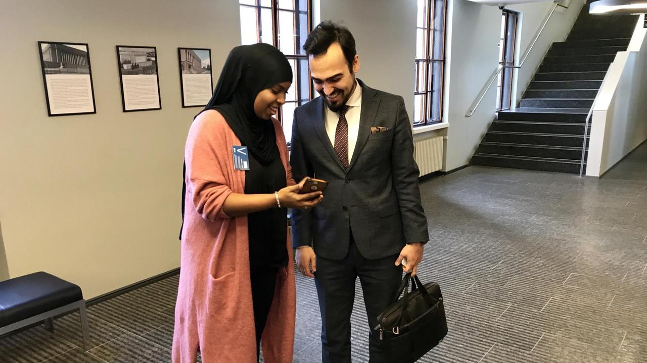 Habiba Ali aus Somalia zeigt ihrem Parlamentskollegen eine Nachricht auf ihrem Smartphone. Sie kommt aus Somalia und kandidiert bei der Parlamentswahl am 14. April für die Sozialdemokraten.