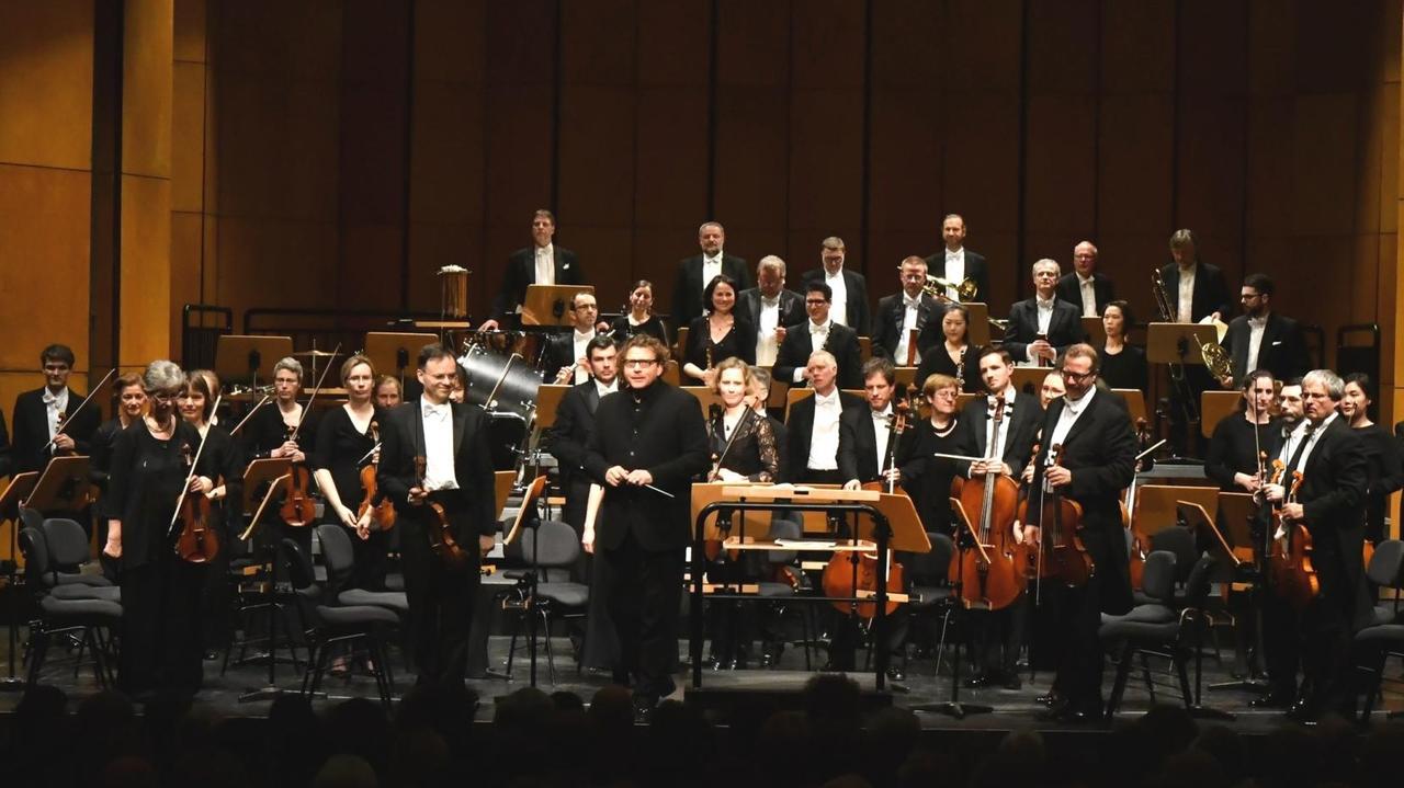 Das Orchester ist für Beifall aufgestanden und umsteht seinen Chefdirigenten Marcus Bosch. Das Orchester ist für Beifall aufgestanden und umsteht seinen Chefdirigenten Marcus Bosch.
