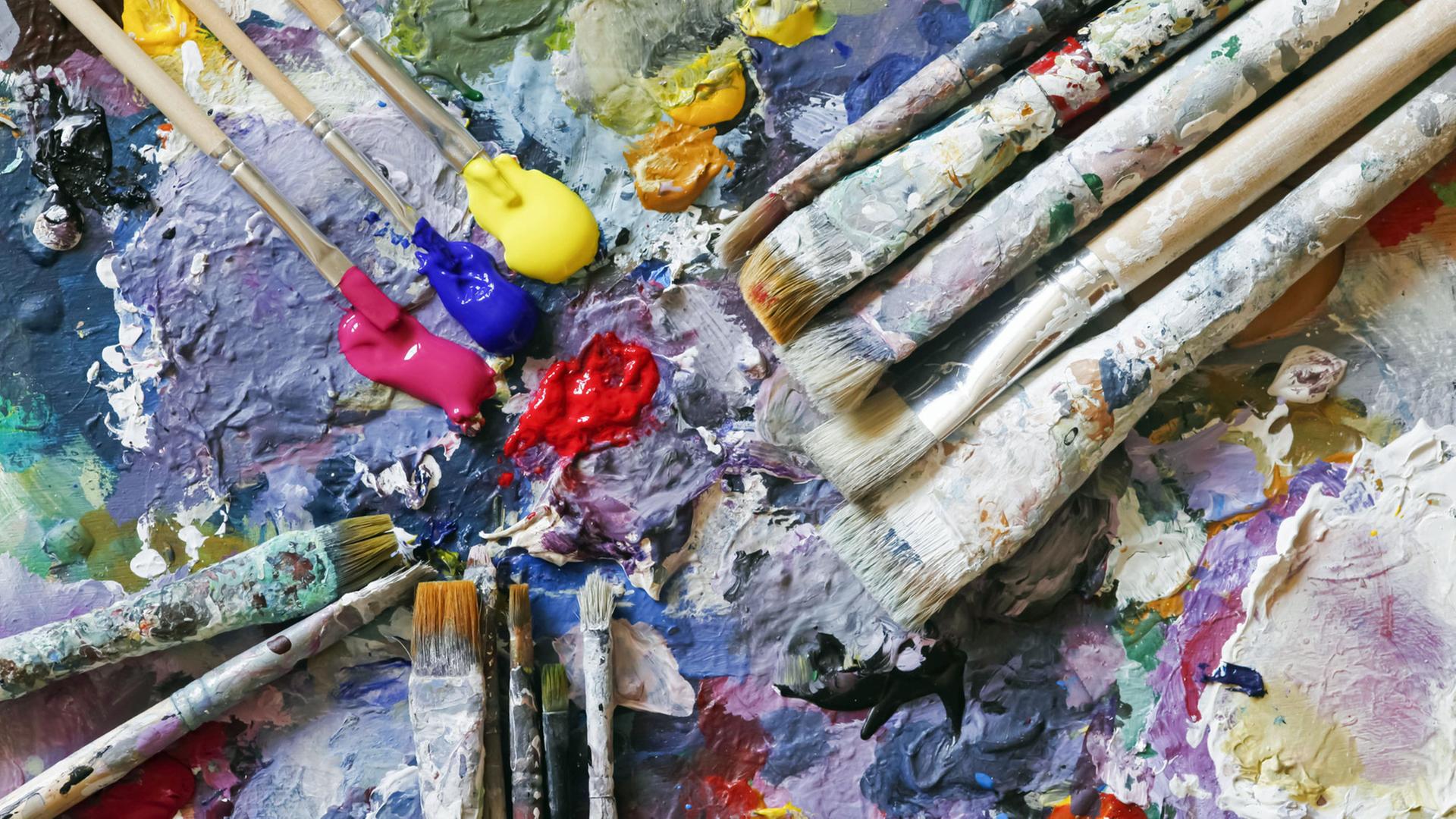Farben und Pinsel auf der Palette eines Künstlers Farben und Pinsel auf der Palette eines Künstlers