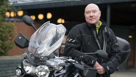 Motorradpfarrer Pfarrer Bernd Schade lehnt am 01.03.2017 in Berlin an seinem Motorrad Triumph Tiger 800.