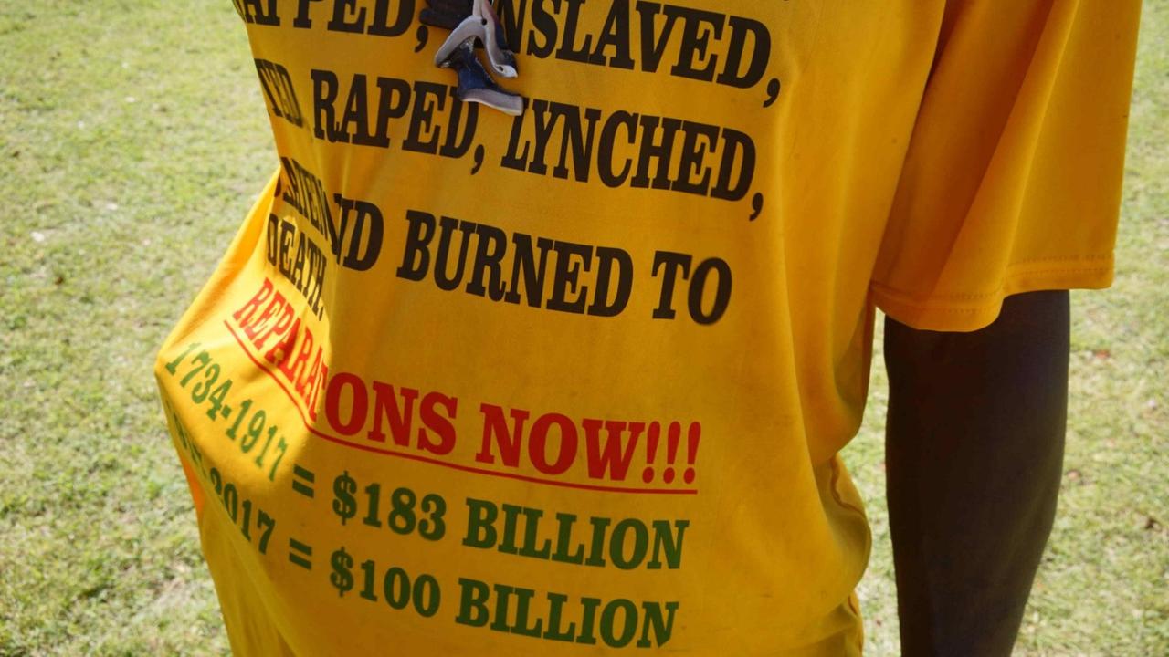 Ein Mann hält sein gelbes T-Shirt in die Kamera, auf dem die genauen Summen für Reparationszahlungen stehen. Ein Mann hält sein gelbes T-Shirt in die Kamera, auf dem die genauen Summen für Reparationszahlungen stehen.