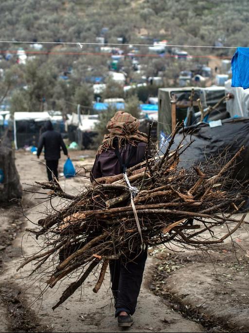 Ein Flüchtling trägt Holz auf dem Rücken, in einem provisorischen Lager neben dem Lager in Moria.