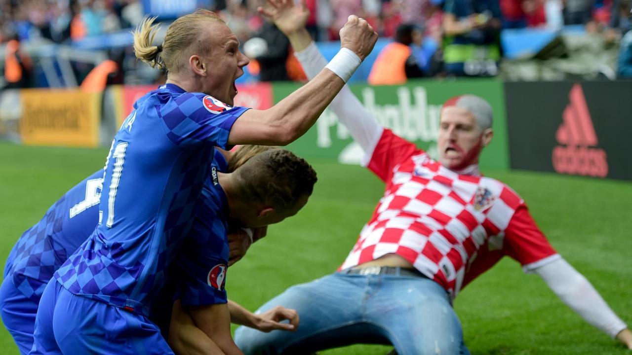 Vida und die anderen beiden Spieler umarmen sich jubelnd am Spielfeldrand. Im Hintergrund rutscht der kroatische Fan auf den Knien heran. Vida und die anderen beiden Spieler umarmen sich jubelnd am Spielfeldrand. Im Hintergrund rutscht der kroatische Fan auf den Knien heran.