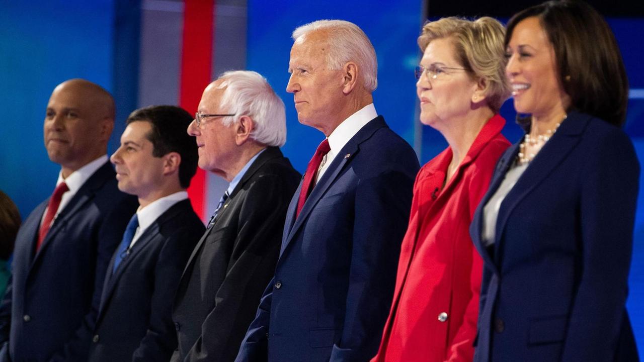 Debattenrunde mit dem demokratischen Kandidaten Cory Booker (l), Pete Buttigieg, Bernie Sanders, Joe Biden, Elizabeth Warren und Kamla Harris im September 2019 in Houston. Sechs Menschen stehen in einer Reihe auf einer Bühne. Debattenrunde mit dem demokratischen Kandidaten Cory Booker (l), Pete Buttigieg, Bernie Sanders, Joe Biden, Elizabeth Warren und Kamla Harris im September 2019 in Houston. Sechs Menschen stehen in einer Reihe auf einer Bühne.