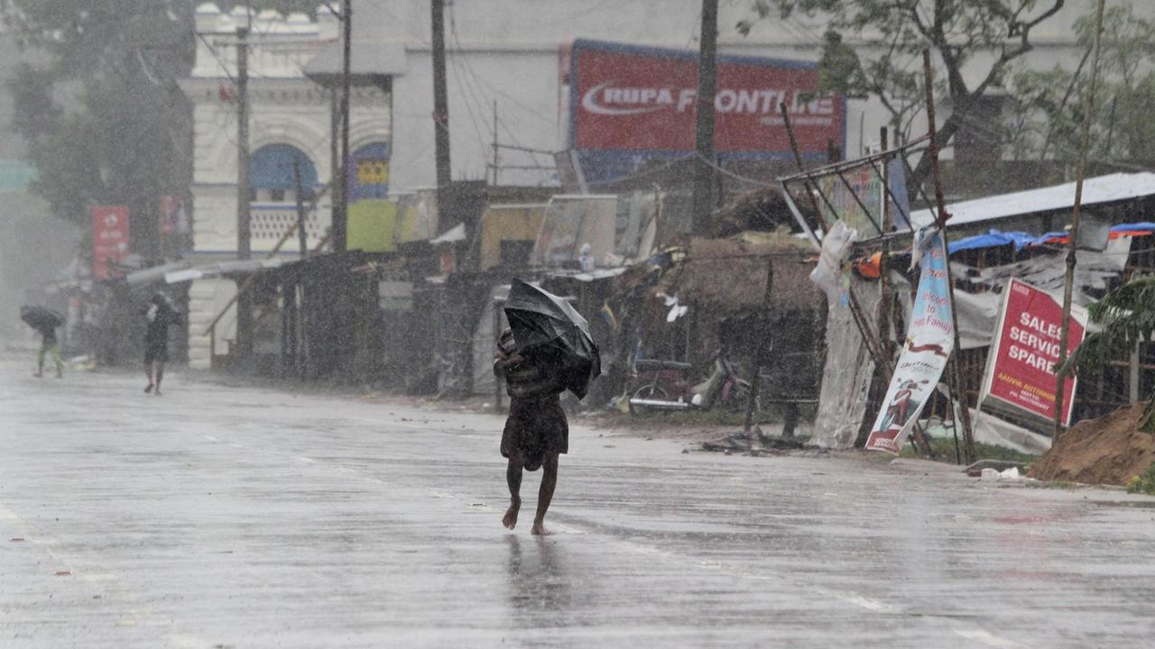 Indien, Chandbali: Menschen schützen sich mit Regenschirmen im ostindischen Bundesstaat Orissa vor Regen des Zyklons «Amphan».