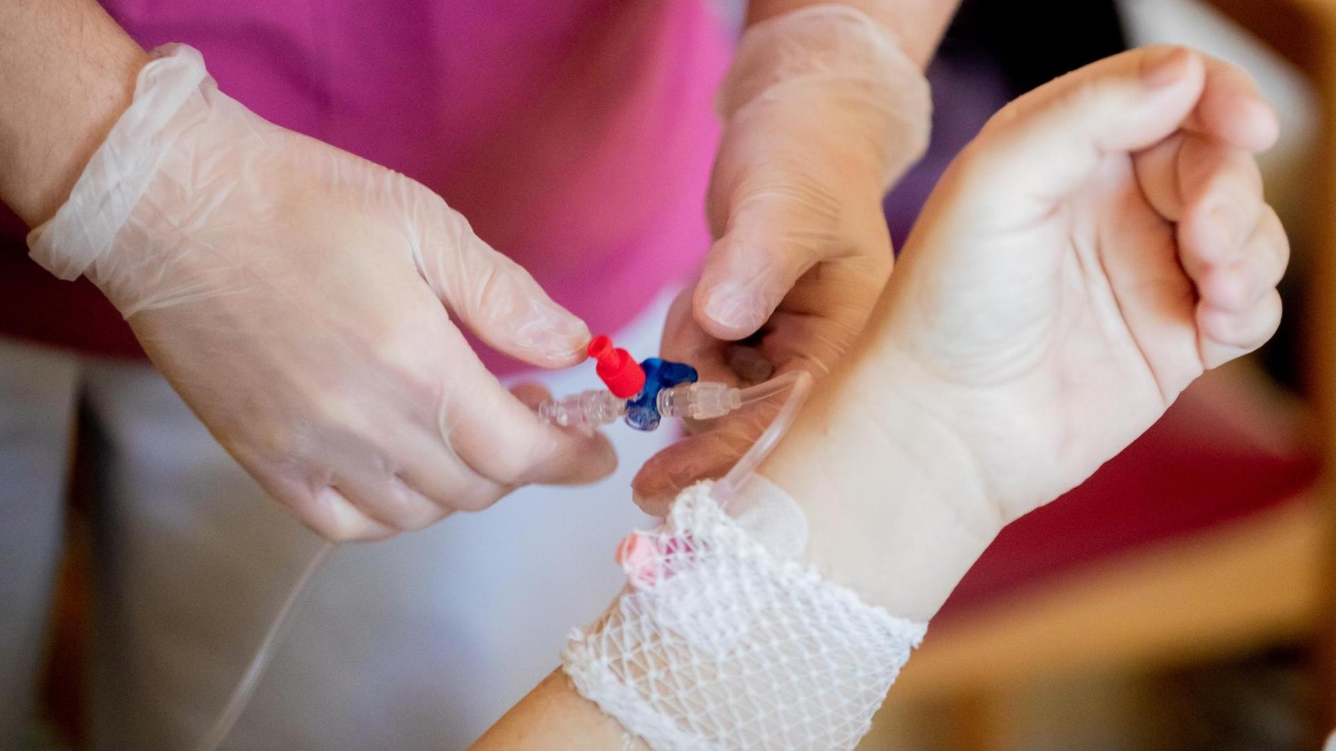 Ein Pfleger versorgt einen Patienten im Krankenhaus mit einer Infusion. Ein Pfleger versorgt einen Patienten im Krankenhaus mit einer Infusion.