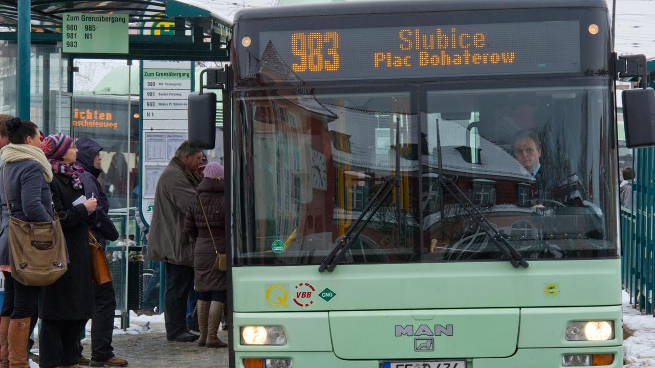 Mintfarbender Linienbus an Haltestelle, Menschen steigen ein und aus. Mintfarbender Linienbus an Haltestelle, Menschen steigen ein und aus.