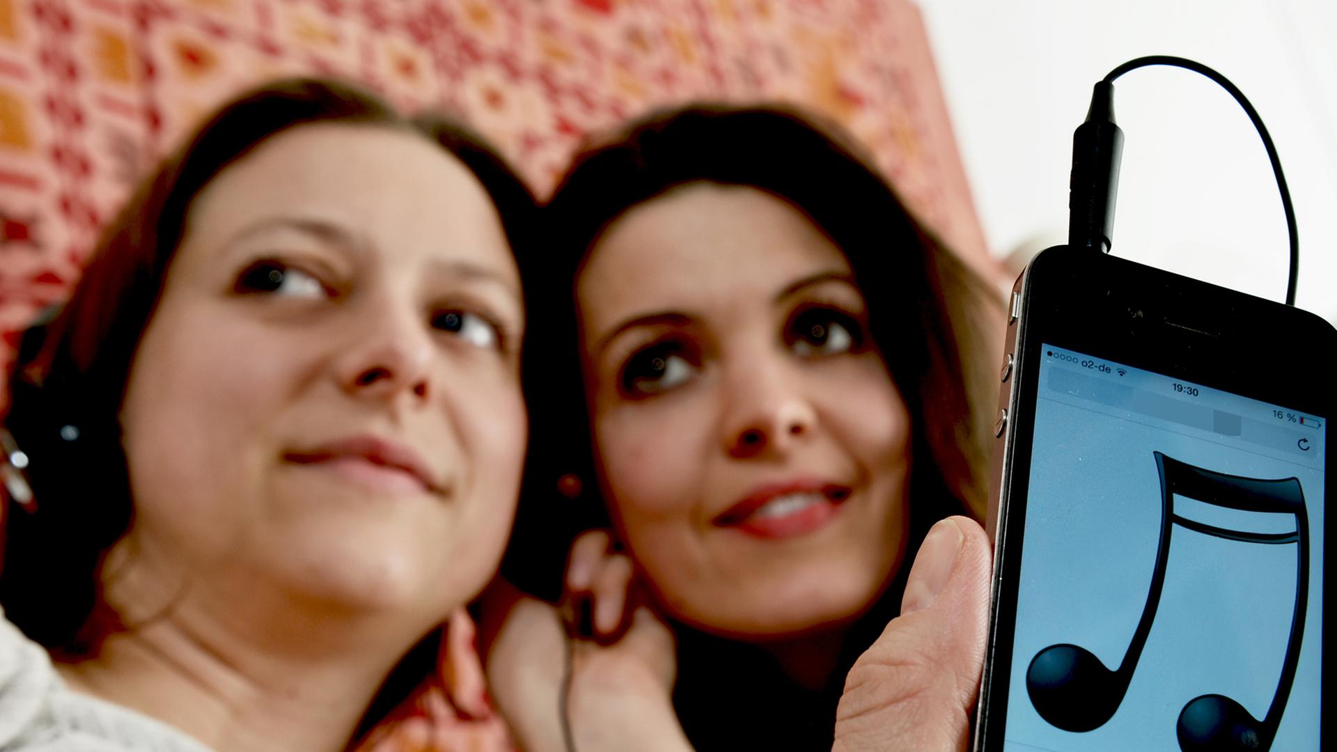 Zwei Frauen hören über ein Smartphone Musik Zwei Frauen hören über ein Smartphone Musik