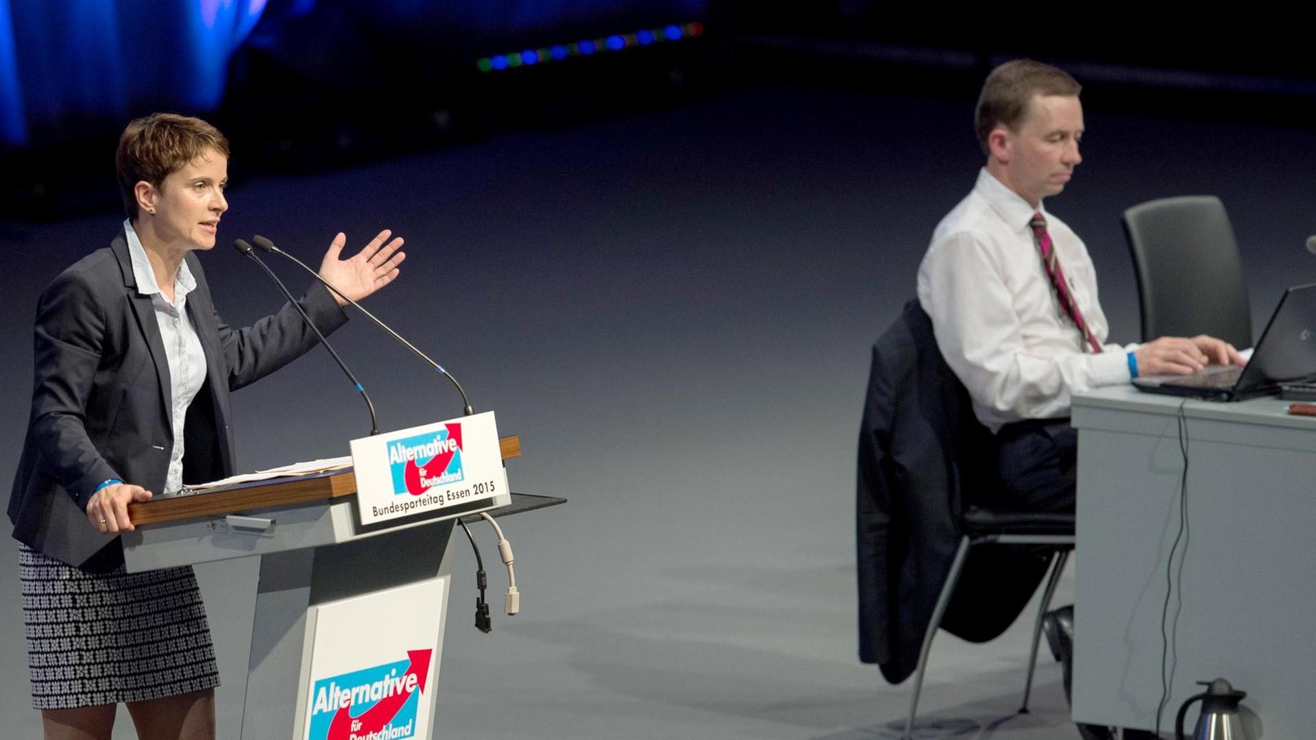 Die AfD-Vorsitzende Petry spricht zu den Delegierten des Essener Parteitags. Der ehemalige Vorstandskollege Lucke sitzt daneben auf dem Podium und arbeitet an seinem Laptop. Die AfD-Vorsitzende Petry spricht zu den Delegierten des Essener Parteitags. Der ehemalige Vorstandskollege Lucke sitzt daneben auf dem Podium und arbeitet an seinem Laptop.