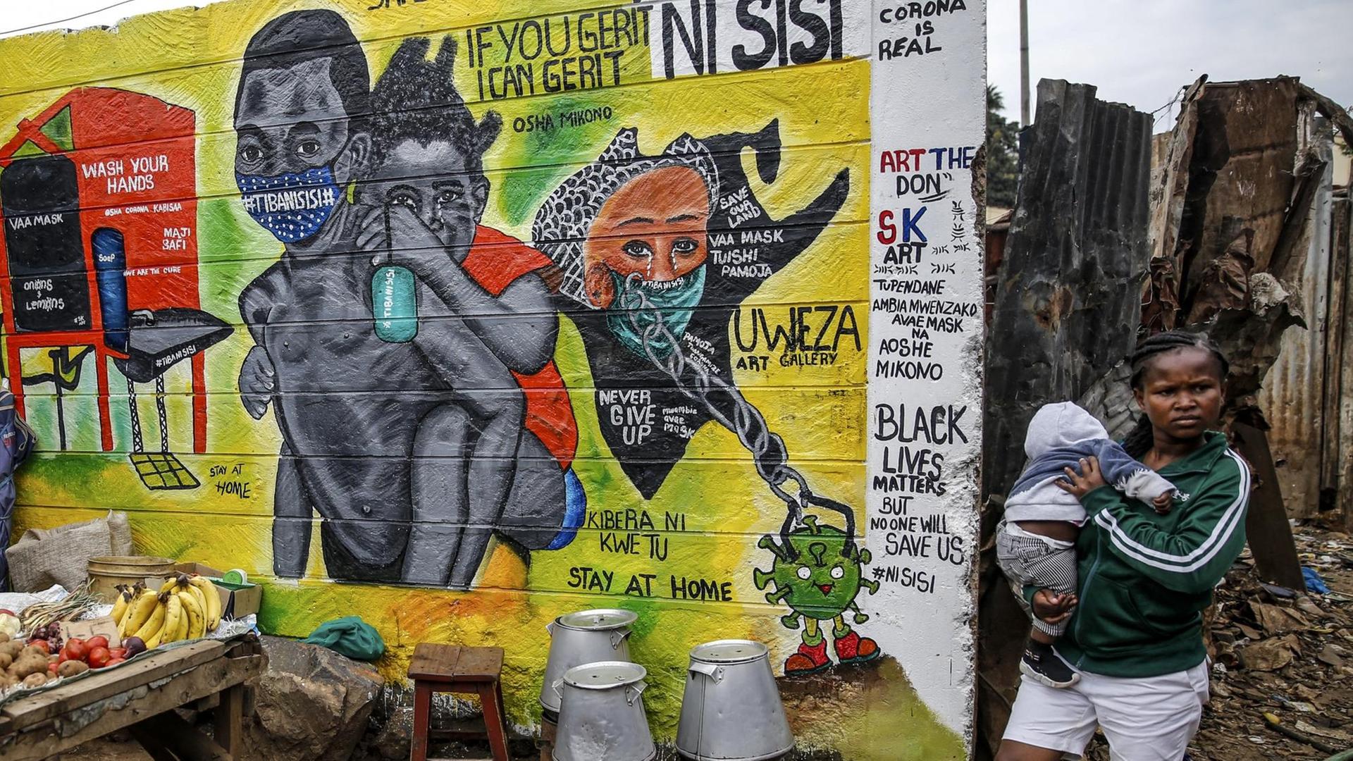 In Kenia steht eine Frau mit einem Kleinkind auf dem Arm neben einem Plakat mit Hinweisen zu Corona-Schutzmaßnahmen