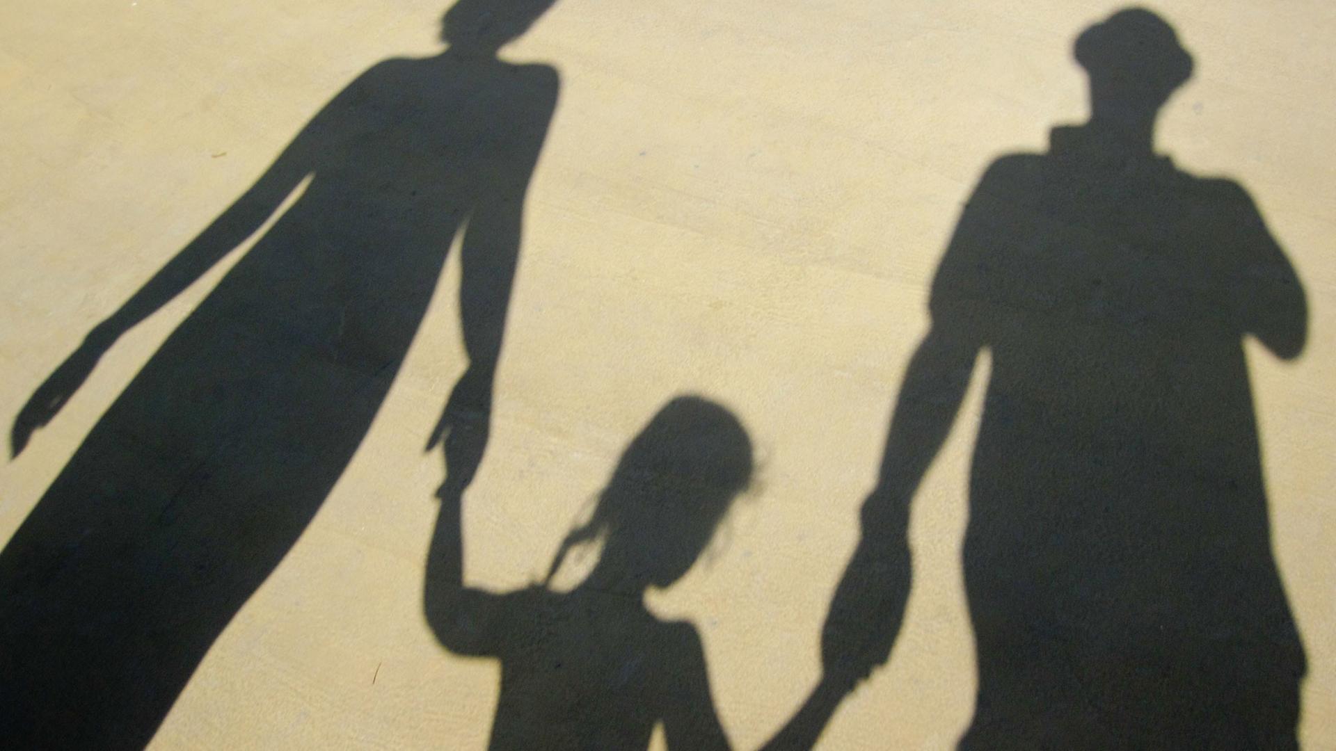 Der Schatten einer Familie, die sich an der Hand hält. Der Schatten einer Familie, die sich an der Hand hält.